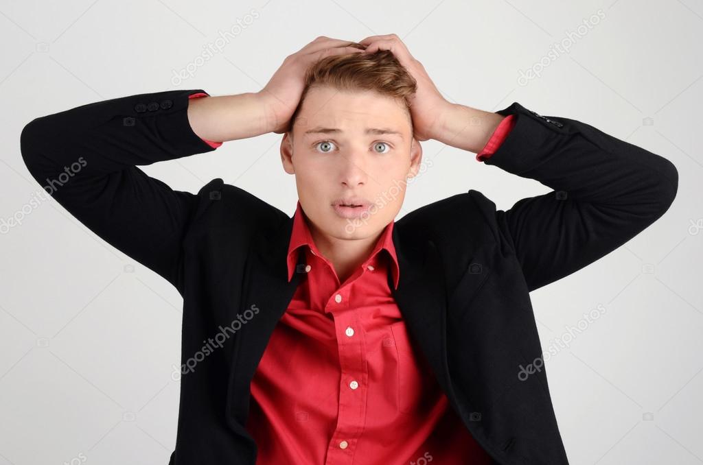 Worry, sadness, desperation. Young business man holding his head frowning with worry.