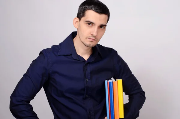 Ученик держит кучу книг под мышкой. Учитель с красочными книгами в руке . — стоковое фото