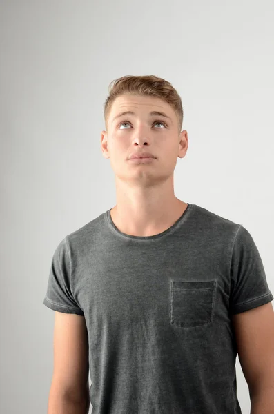 Retrato de un hombre mirando hacia arriba. Joven atractivo hombre con estilo en camiseta gris . — Foto de Stock