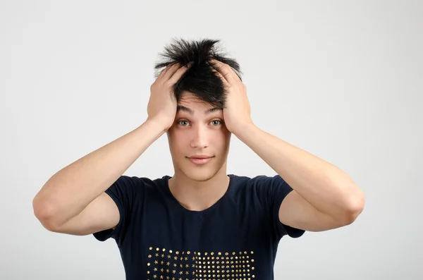 Young man with crazy hair holding his head confused. Bad hair day. — Stock Photo, Image