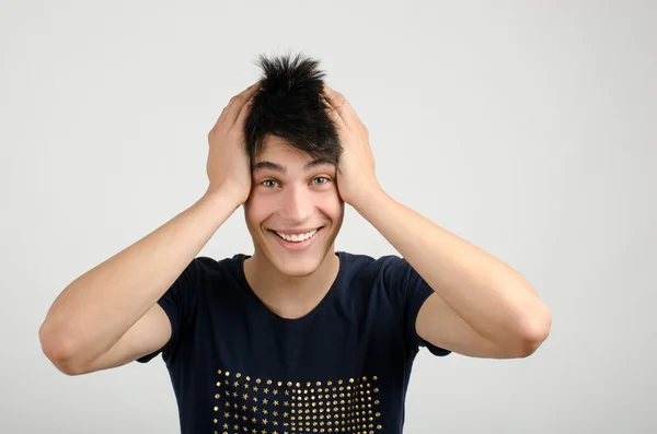 Ung man med galna hår håller hans huvud leende. man är glad överraskad och förvånad. — Stockfoto