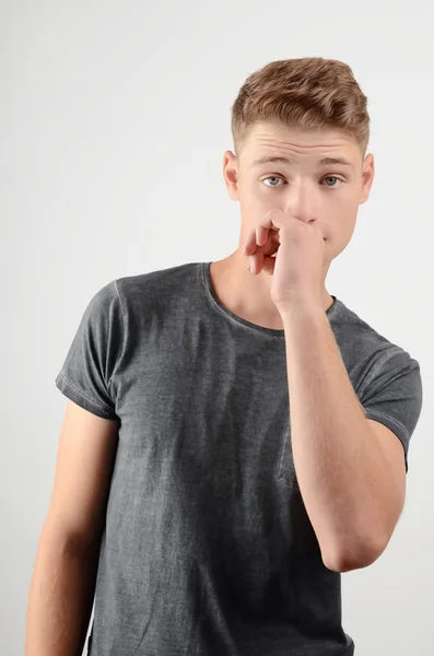 Young man smelling something bad. Disgusting odor. Guy frowning and holding his hand at his nose. — Stock Photo, Image