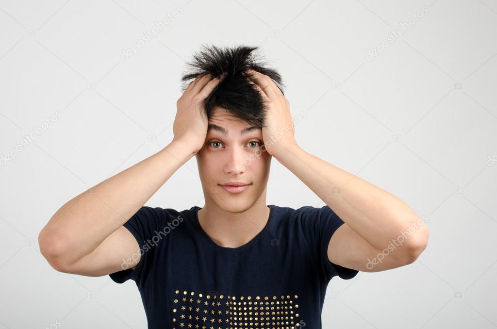 Young man with crazy hair holding his head confused. Bad hair day.