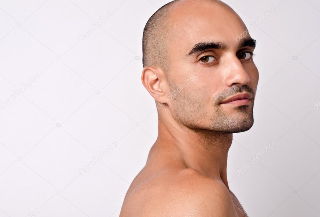 Portrait of a beautiful bald man looking over his shoulder. Profile of a handsome bald Caucasian man.