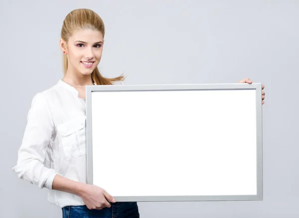 Young girl smiling and holding a white blank board. — Stock Photo, Image
