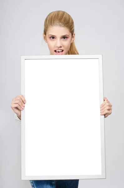 Young girl amazed holding in front a white blank board. — Stock Photo, Image