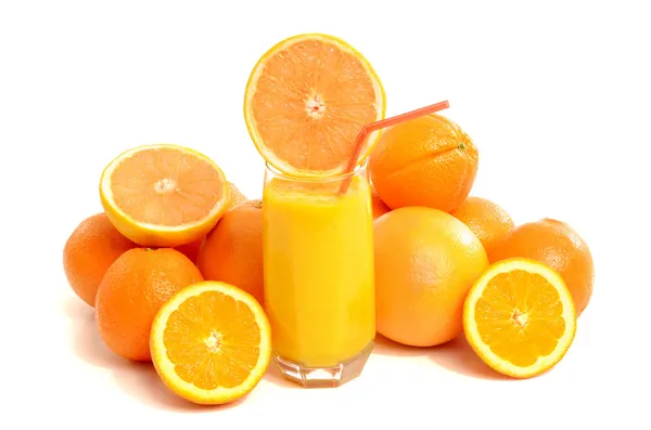 Pile of grapefruits and oranges with a glass of fresh grapefruit juice. — Stock Photo, Image