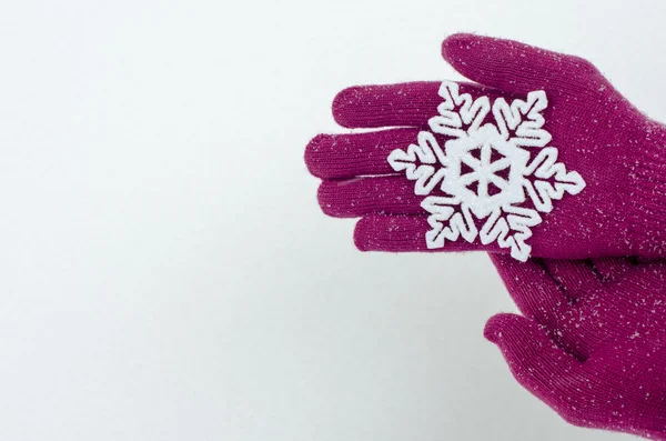 Feche as mãos usando luvas rosa segurando um grande floco de neve . — Fotografia de Stock