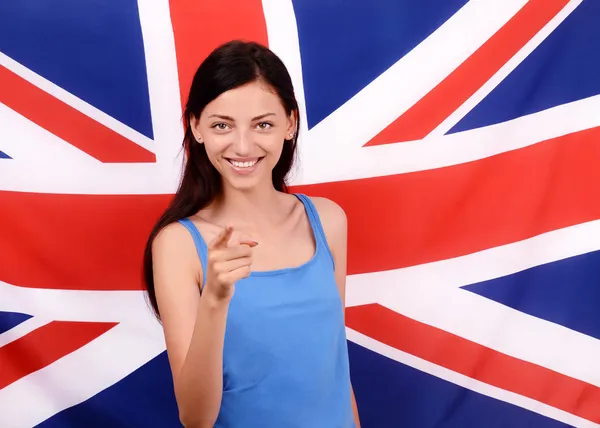 Retrato de uma bela menina britânica sorrindo e apontando na frente para você . — Fotografia de Stock