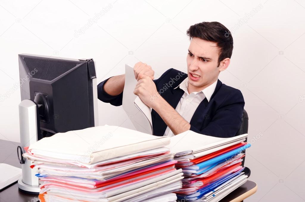 Angry business man tearing up paper work.