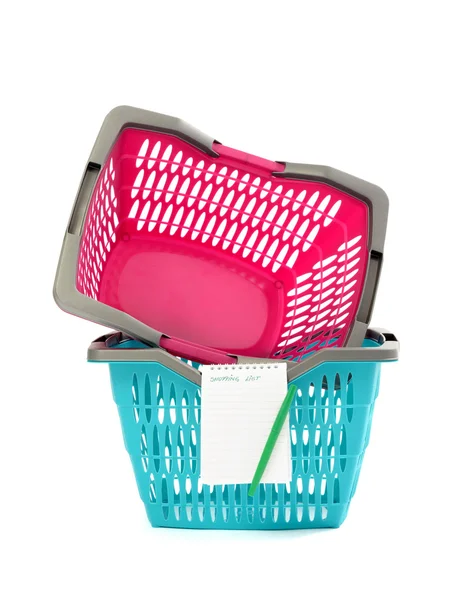Blue and pink plastic shopping basket with blank shopping list isolated on white. — Stock Photo, Image
