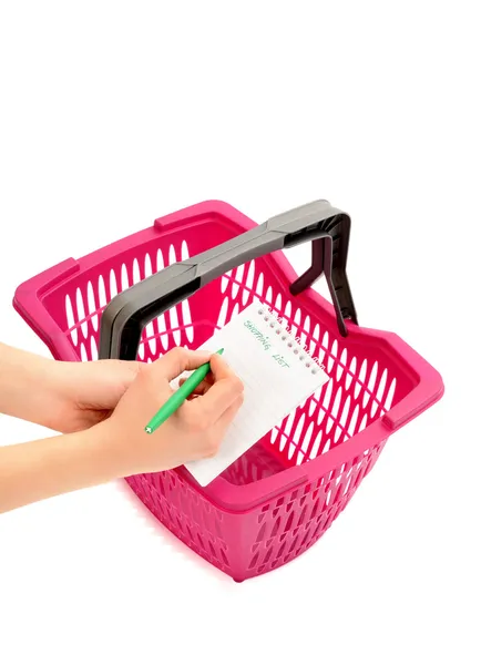 Frau schreibt Einkaufsliste und rosa Einkaufskorb. — Stockfoto
