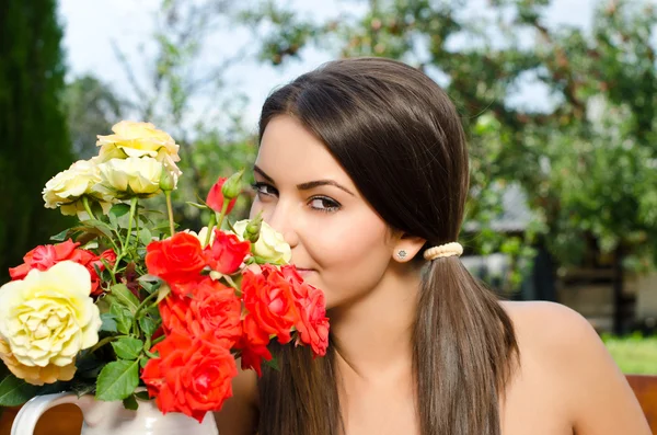 Mooie vrouw in de tuin bloemen ruiken. — Stockfoto