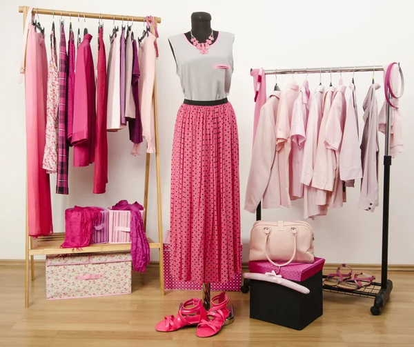 Lemari pakaian dengan pakaian merah muda diatur pada gantungan dan pakaian pada manekin . — Stok Foto