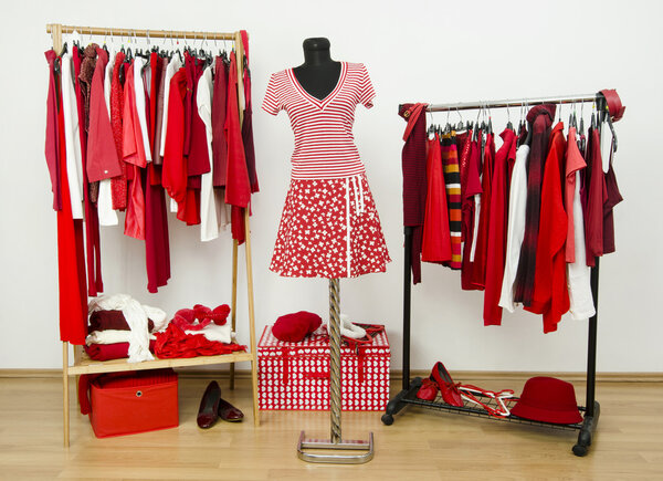 Dressing closet with red and white clothes arranged on hangers and an outfit on a mannequin.