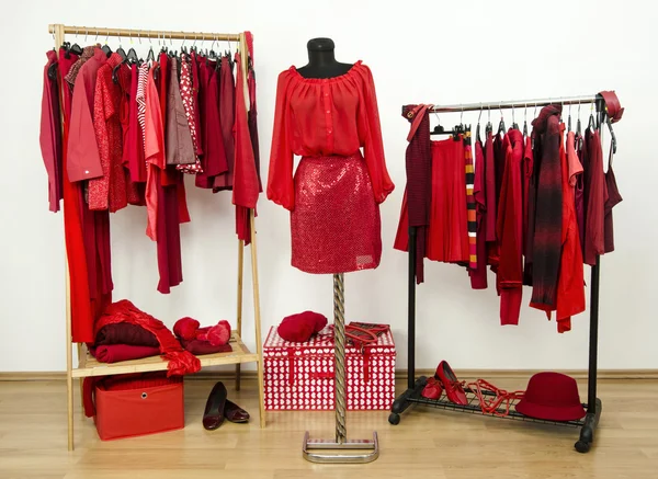 Dressing closet with red clothes arranged on hangers and an outfit on a mannequin. — Stock Photo, Image