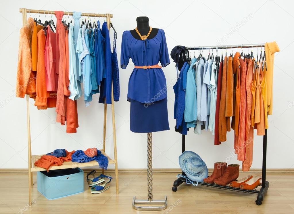 Dressing closet with complementary colors blue and orange clothes arranged on hangers and an outfit on a mannequin.