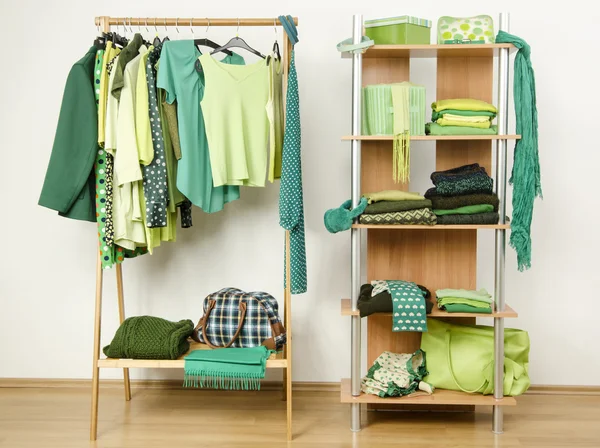 Dressing closet with green clothes arranged on hangers and shelf. — Stock Photo, Image