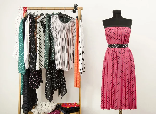 Armário de vestir com bolinhas roupas arranjadas em cabides e um vestido rosa em um manequim . — Fotografia de Stock