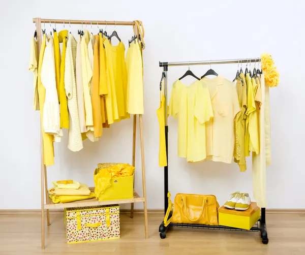 Dressing closet with yellow clothes arranged on hangers. — Stock Photo, Image