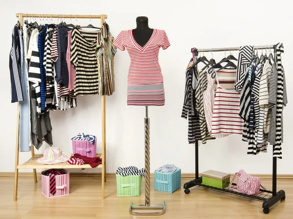 Kleiderschrank mit gestreiften Kleidern auf Kleiderbügeln und einem Outfit auf einer Schaufensterpuppe. — Stockfoto