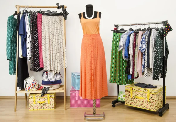 Klä garderob med prickar kläder ordnade på galgar och en orange outfit på en skyltdocka. — Stockfoto