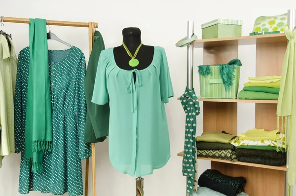 Armário de vestir com roupas verdes dispostas em cabides e prateleira, roupa em um manequim . — Fotografia de Stock