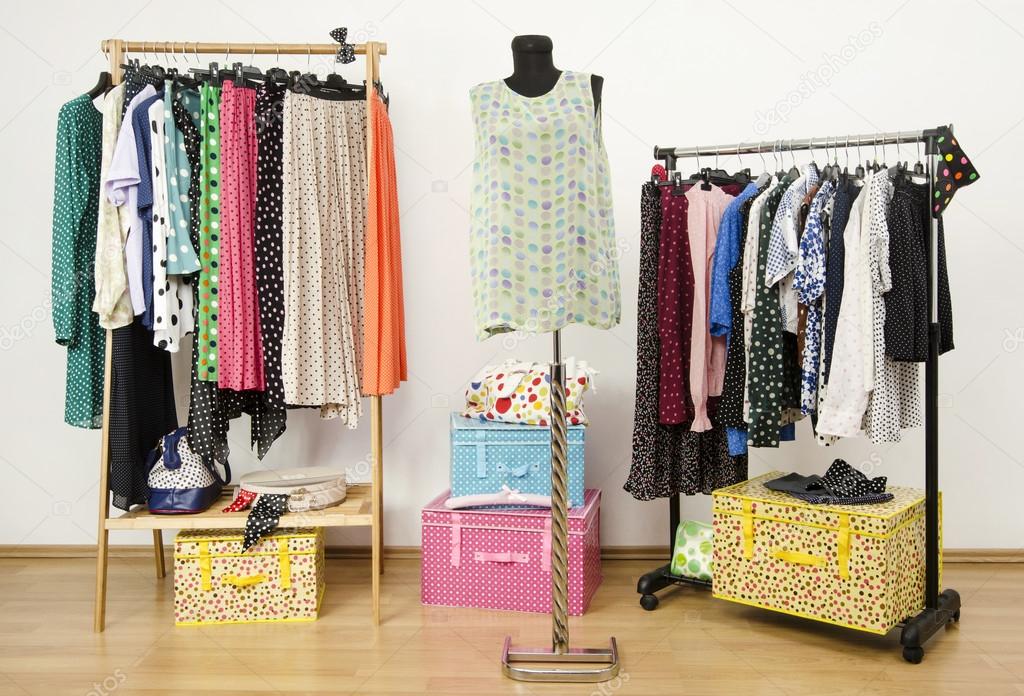 Dressing closet with polka dots clothes arranged on hangers and an outfit on a mannequin.