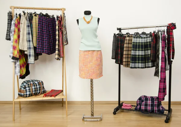 Kleiderschrank mit karierten Kleidern auf Kleiderbügeln und einem Outfit auf einer Schaufensterpuppe. — Stockfoto