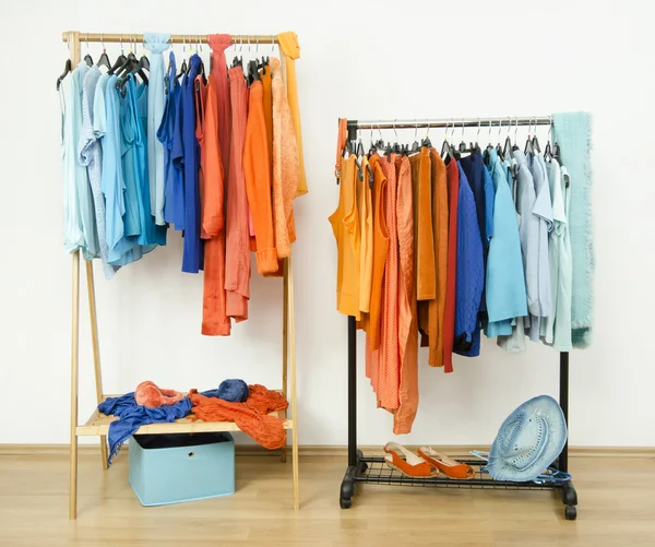 Roupeiro com cores complementares laranja e azul roupas penduradas em um rack bem organizado . — Fotografia de Stock