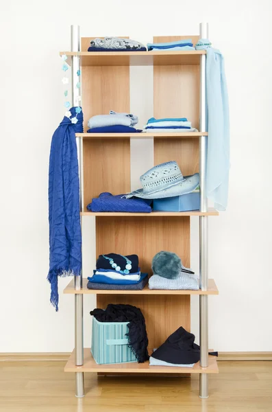 Blue clothes nicely arranged on a shelf.