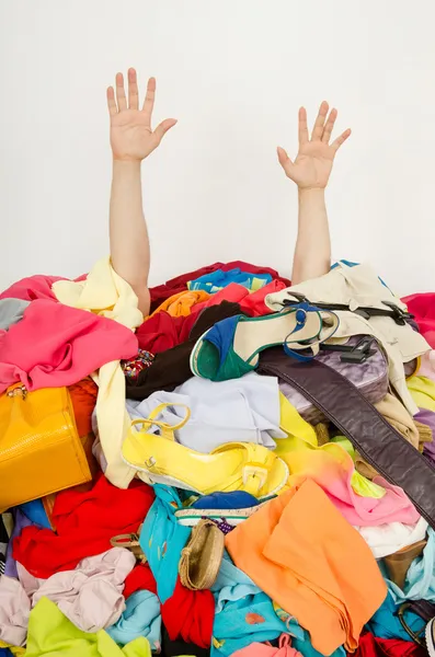 Mãos de homem estendendo-se de uma grande pilha de roupas e acessórios . Imagens Royalty-Free