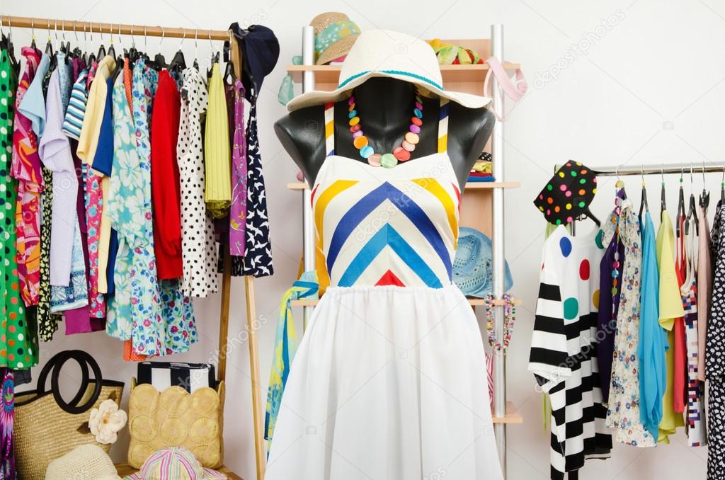 Wardrobe with summer clothes nicely arranged and a beach outfit on a mannequin.
