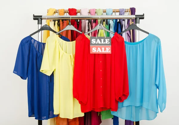 Cute red, yellow, blue blouses displayed on hangers with the sale sign. — Stock Photo, Image