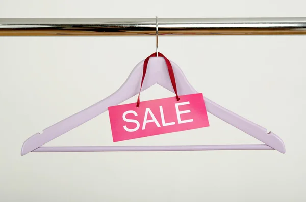 Empty hanger on a rack of clothes with the sale sign.