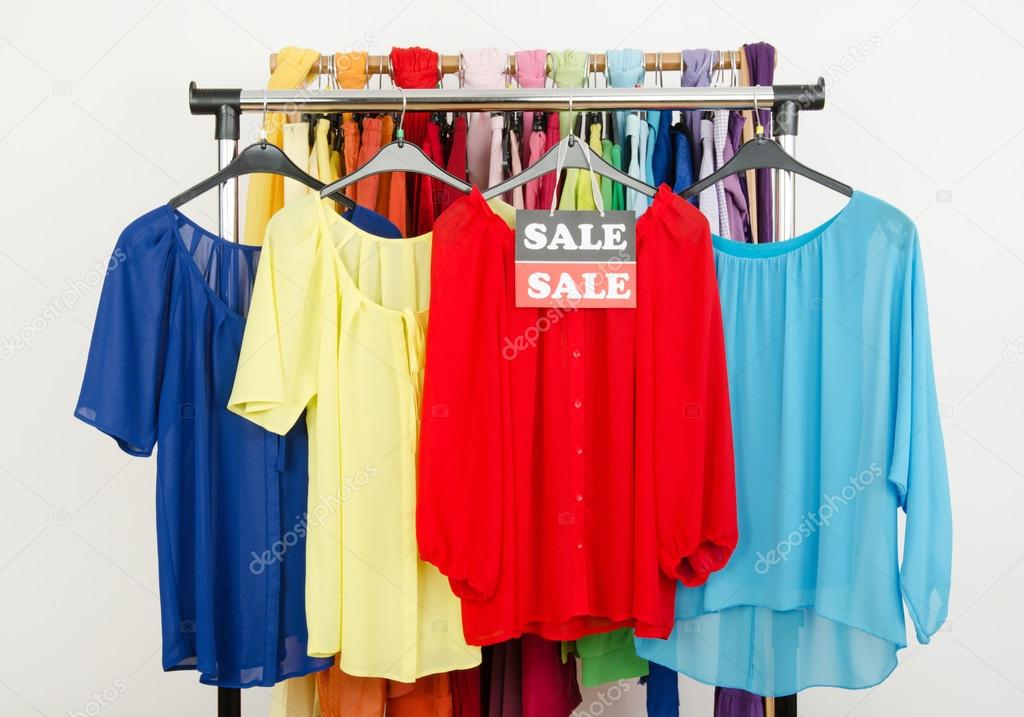 Cute red, yellow, blue blouses displayed on hangers with the sale sign.