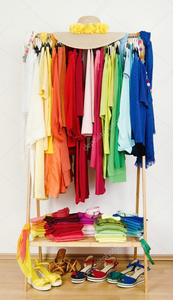 Wardrobe with summer clothes nicely arranged by colors.