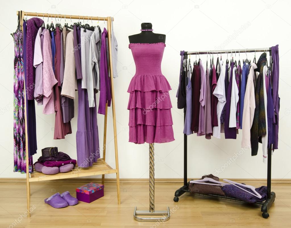 Wardrobe with purple clothes arranged on hangers and a dress on a mannequin.