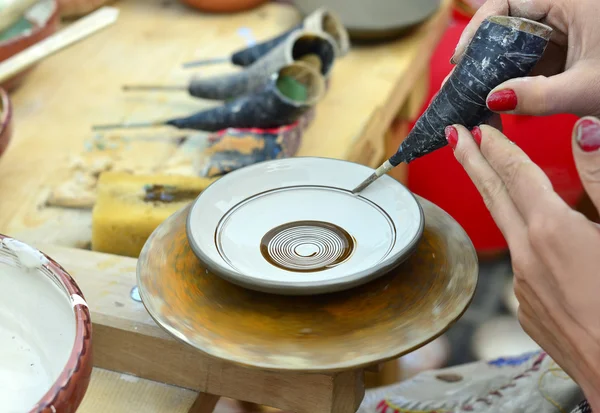 Close-up of hands decorating in circles a plate with paint. — Stock Photo, Image