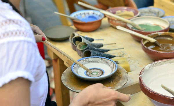 Close-up of hands decorating in circles a plate with paint. — Stock Photo, Image