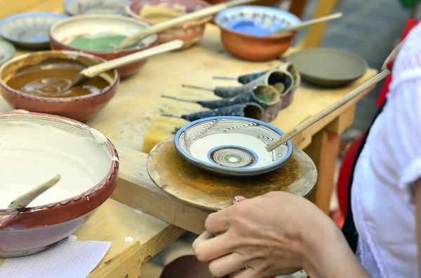 Close-up of hands decorating in circles a plate with paint. — Stock Photo, Image