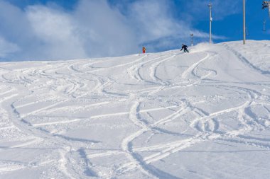Kahverengi saçlı, kayak kıyafeti giyen ve kar üzerinde bir sürü izi olan güzel bir kar tepesinde kayak yapan bir kadın, yandan manzara, Stryn Norveç, yatay