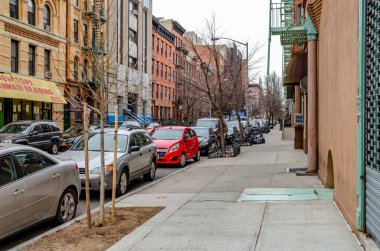 Harlem 'de perakende mağazası ve farklı eski bina cepheleri olan caddeler, caddeye park edilmiş arabalar.