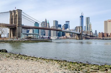 Brooklyn Köprüsü New York. Köprüsü 'nde inşaat alanı var. Manhattan Skyline ve One World Trade Center İnşaat Alanı. Arka planda, Hudson Nehri' nde, plajda ve atlıkarıncada.