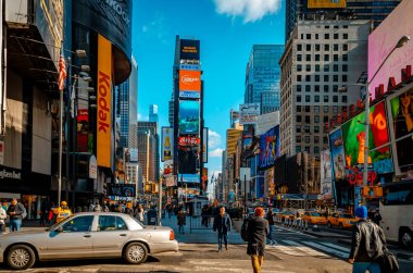 Time Square New York gökdeleni üzerinde reklam olan, caddelerde çok trafik olan, akşam, yatay yürüyen insanlar.
