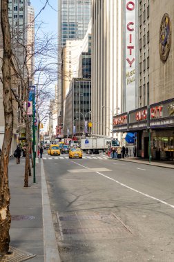 Radio City Music Hall, New York City caddeleri ve kaldırımları önde, trafik yoğun, sarı taksi, gündüz vakti sokakta, dikey