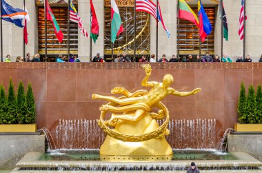 Kış boyunca Rockefeller Center 'da altın Prometheus heykeli. Arka planda bayraklar ve New York City' de buz pateni yapan insanlar.