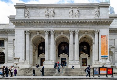 New York Halk Kütüphanesi girişi. İnsanlar gün ışığında binaya girip çıkıyorlar.