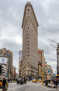Flatiron Binası sokak ve yaban kırlangıçları olan New York şehri, gündüz vakti bulutlu sarı taksiler, alçak açılı, dikey manzaralı