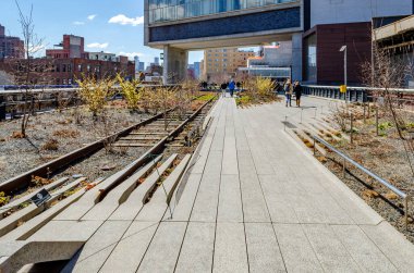 İnsanlar New York 'taki High Line Çatı Parkı' nda demiryolu hattıyla yürüyor.